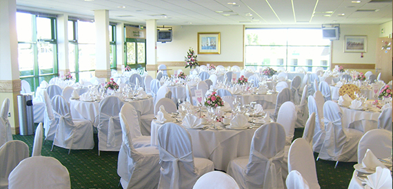 Function suite with round tables in white chair covers and pink floral displays.