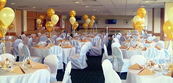 Function room set for dinner with gold and cream balloon clusters.