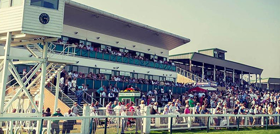 Grandstand crowds watching a race at Great Yarmouth Racecourse.