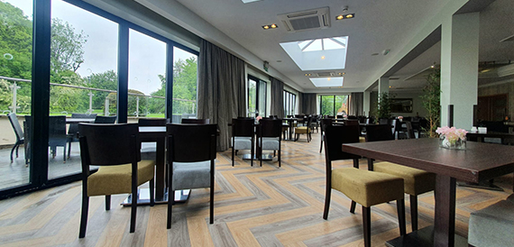 Conservatory dining area with dark wood tables and views over the golf course.