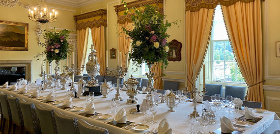Formal dining table set with silverware and tall floral centrepieces