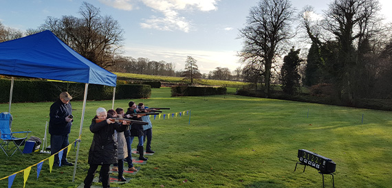 Guests clay pigeon shooting on the lawn beneath a blue gazebo