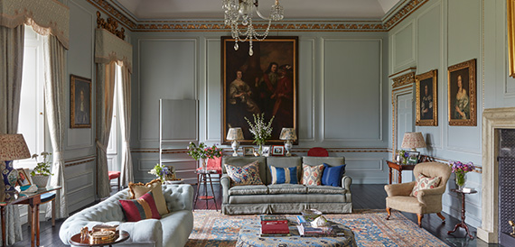 Elegant sitting room with pale panelled walls, portraits and sofas