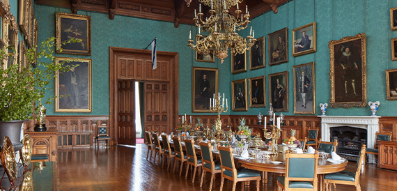 Grand dining hall with teal walls, oil portraits and a long dining table