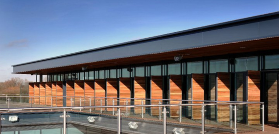 Modern building exterior with angled cedar cladding along the glass frontage