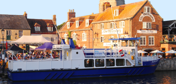 Boat docked beside a historic harbourside town with visitors gathered
