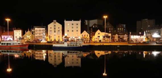 Harbour town illuminated at night with buildings reflected in the water
