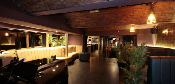Brick-vaulted lounge with cream banquette seating and potted plants