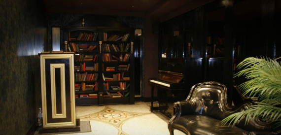 Library-style room with bookshelves, a piano and a leather armchair