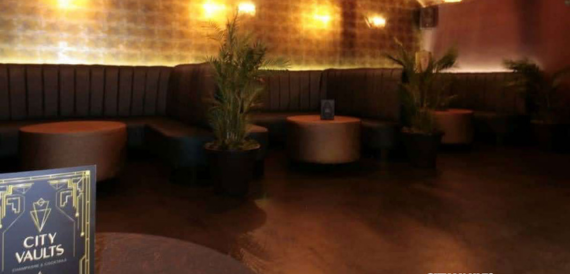 Dark lounge with a curved sofa booth and a potted plant