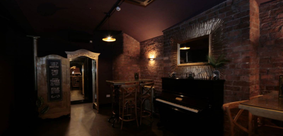 Dim corridor with exposed brick, a mirror and a piano nook