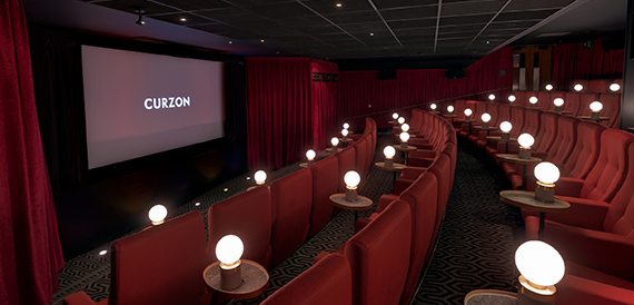 Cinema auditorium with red seats and individual table lamps beside each row