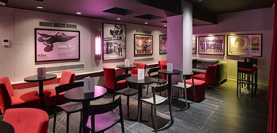 Cafe seating with red chairs beneath framed film posters