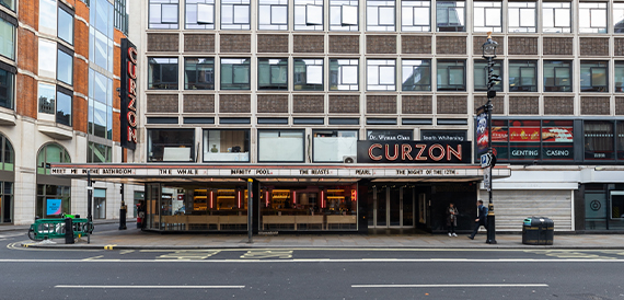 Curzon's exterior with an illuminated marquee listing current film titles