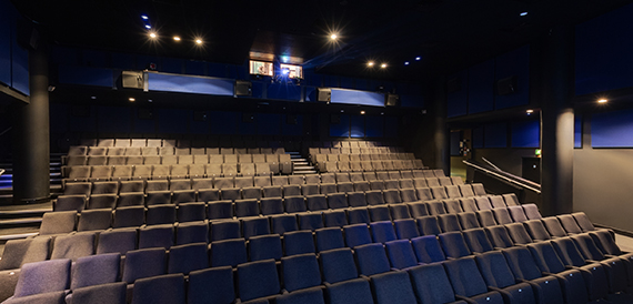 Cinema auditorium with blue-grey seats on a steeply raked floor