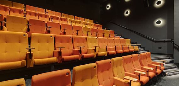 Cinema auditorium with orange tip-up seats and circular ceiling lights