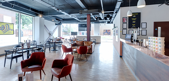 Lounge area with red armchairs, black tables and a long bar