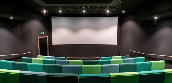 Screening room with curved rows of green seats facing the screen