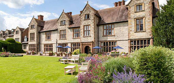 Billesley Manor Hotel's stone facade overlooking colourful garden borders