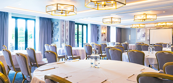 Conference room set boardroom-style with round tables and pendant lighting