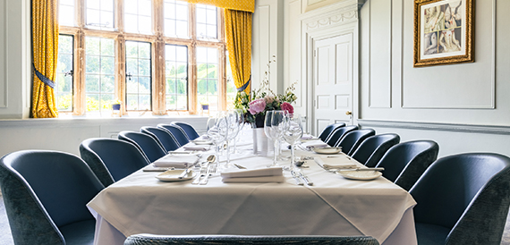 Private dining room with a long table, blue chairs and gilt-framed art