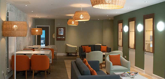 Cosy lounge corner with wicker pendant lights and orange armchairs