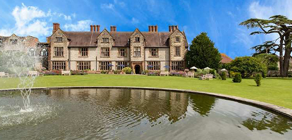 Billesley Manor Hotel viewed across its lake, framed by lawns