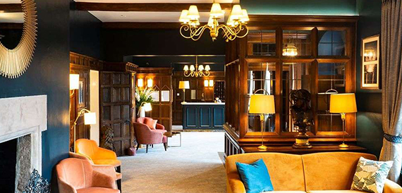 Dark oak-panelled bar lounge with an ornate chandelier and leather armchairs