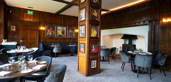Wood-panelled lounge with a screen of framed portraits and blue armchairs