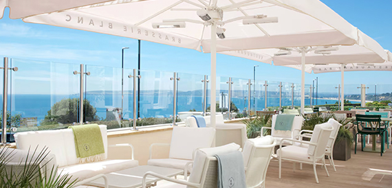 Terrace with white umbrellas and loungers overlooking the sea