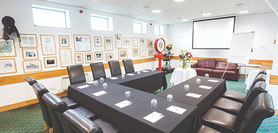 Boardroom with a U-shaped table, leather chairs and framed racing memorabilia