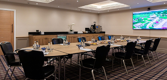Boardroom with a U-shaped table, black chairs and an estate view on screen