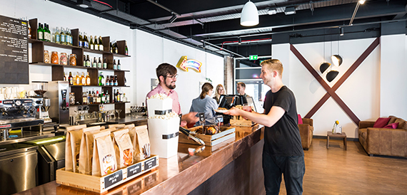 Bar staff serving a customer at a counter stocked with snacks