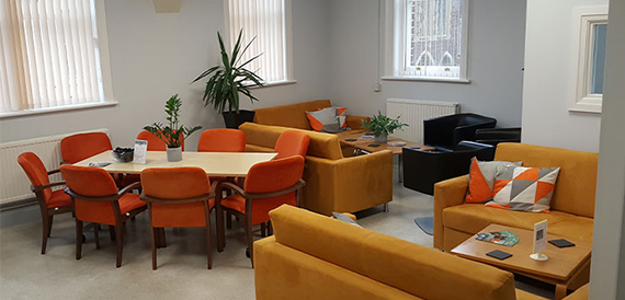 Breakout lounge with orange sofas, armchairs and potted plants