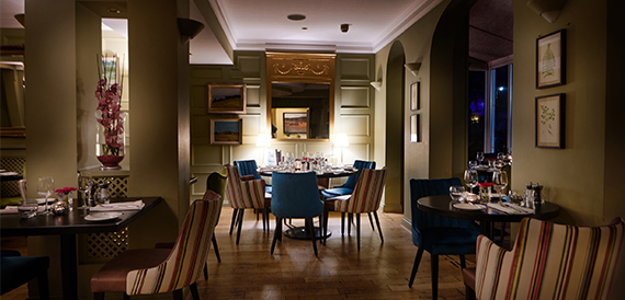 Restaurant with dark wood panelling, round tables and teal chairs