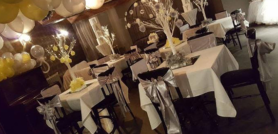 Event space set with white-clothed tables, balloon decor and tree centrepieces