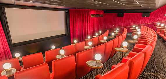 Curved auditorium with red seats and individual lamps at every row