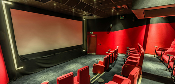 Screening room with an illuminated screen frame and red seats