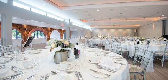 Reception hall with a long banquet table and exposed brick archways beyond.