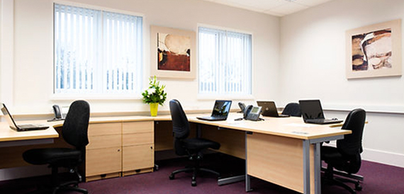 Shared office space with desks, laptops and artwork on the walls