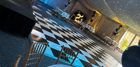Marquee event with a checkerboard dance floor, light-up number decoration and balloons