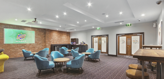 Breakout lounge with blue armchairs, high tables and an exposed brick wall