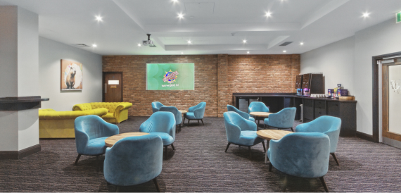 Breakout lounge with blue velvet armchairs, a yellow sofa and exposed brick