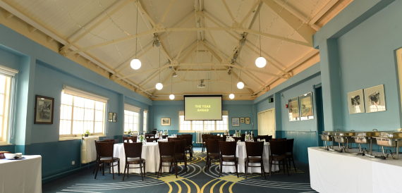 Blue hall set classroom-style with dark chairs facing a screen