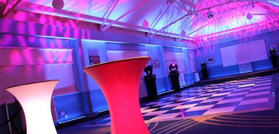 Dance floor lit in pink and blue with glowing cocktail tables