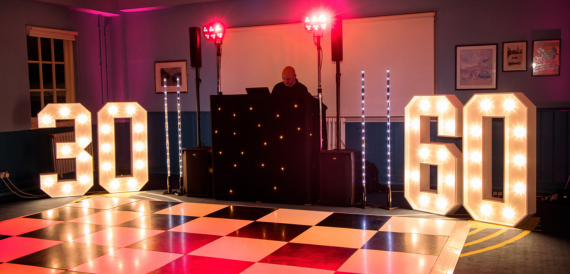 DJ booth with illuminated number lights beside a chequered dance floor