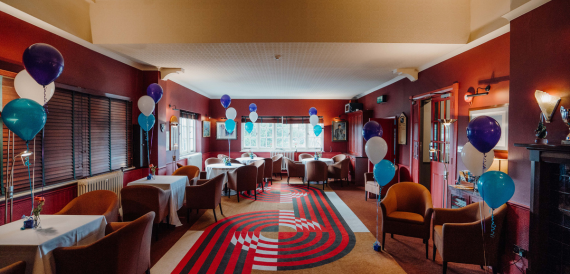 Red-walled lounge with armchairs, balloons and a patterned rug
