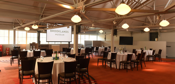 Brooklands Museum hall set with round tables on an orange carpet