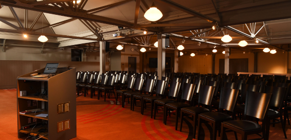 Hall set theatre-style with dark leather chairs on an orange carpet