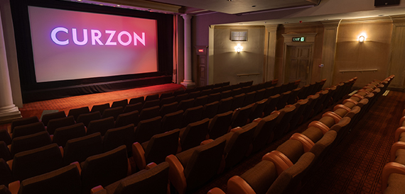 Cinema auditorium with red seats and a purple-lit Curzon screen